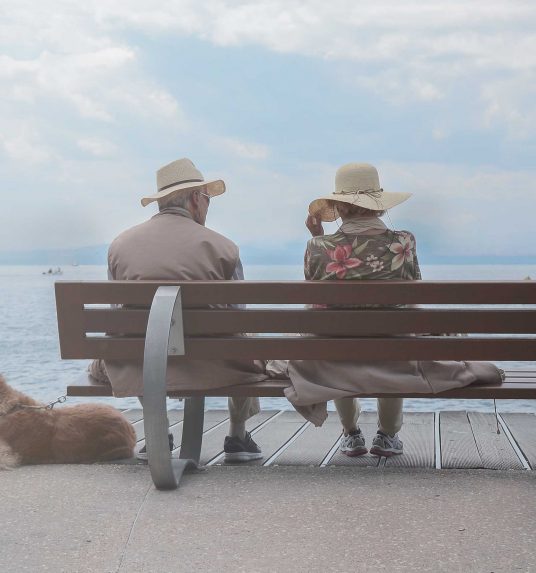 Two elderly people sitting on a bench