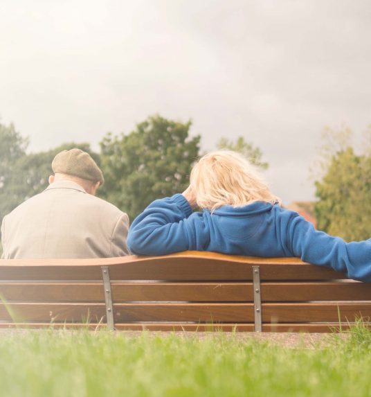 Senior father and adult daughter on a bench having a conversation
