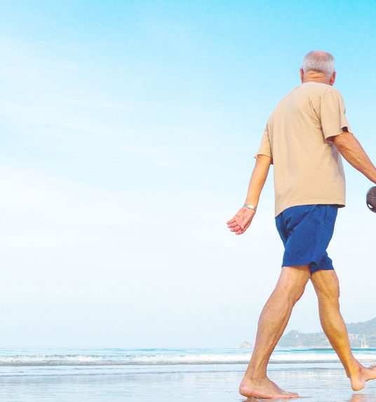 Man walks beach to keep brain active and healthy